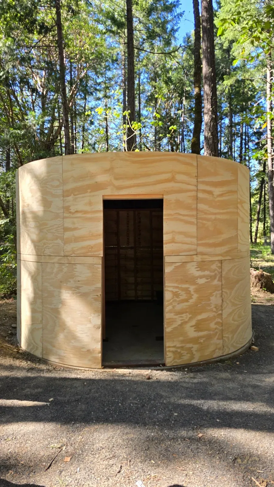 Custom round sauna exterior wrapped in curved plywood sheathing before weatherproofing
