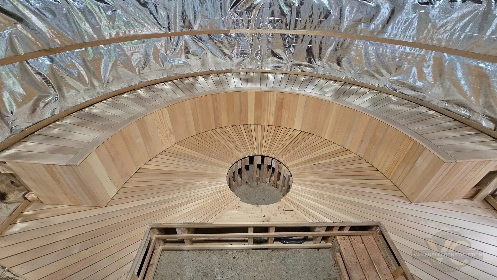 Custom sauna bench and wood floor boards being cut into a sunburst pattern around the heater opening
