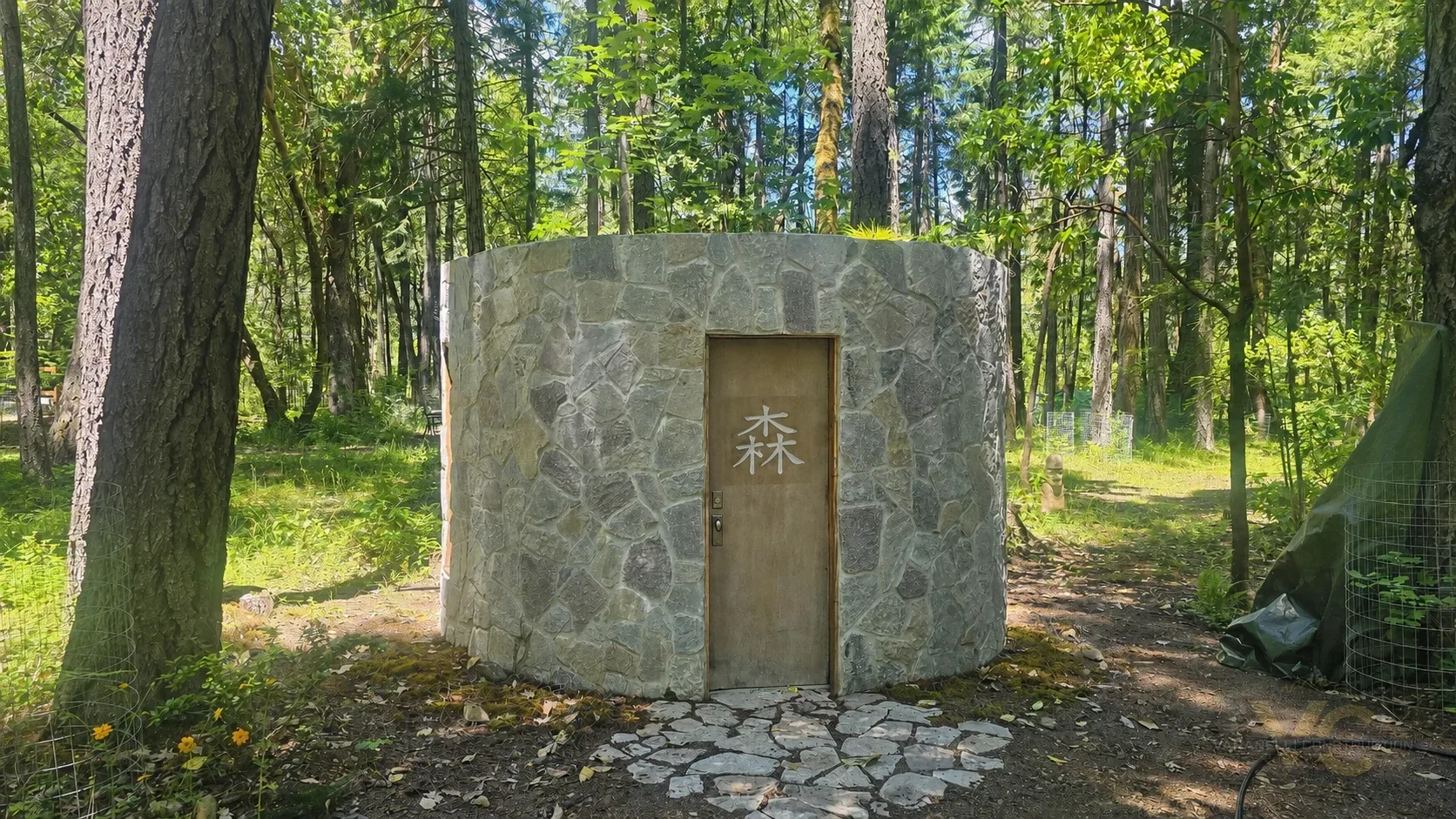 Finished round sauna exterior in the Applegate Valley with stone masonry and planted living roof