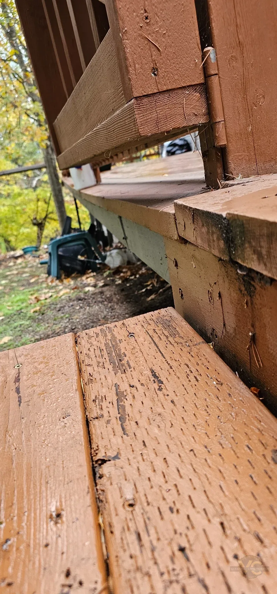 Close view of deteriorated cedar deck boards and support connections before repair