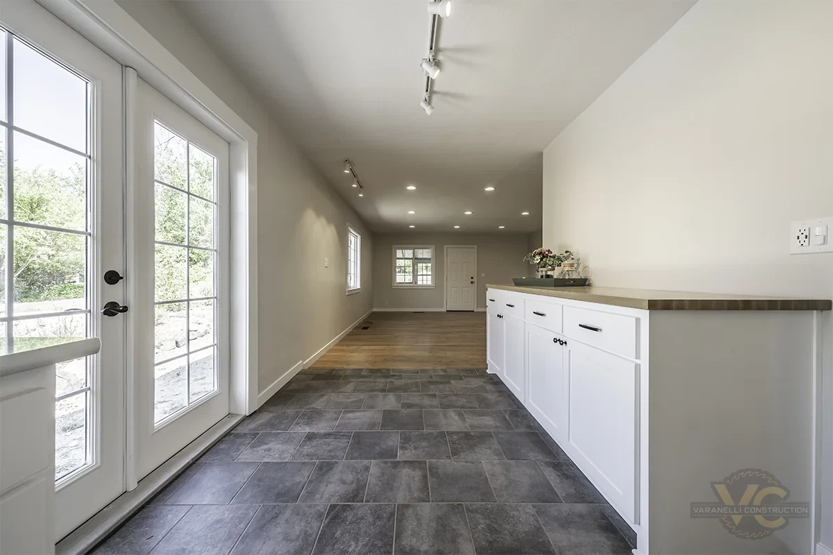 Finished Grants Pass kitchen and dining area with white cabinets and gray tile flooring