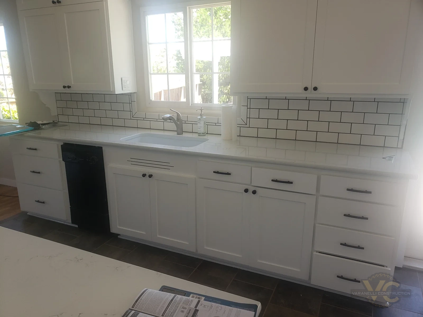 Kitchen remodel progress showing white cabinets, tiled backsplash and tile flooring