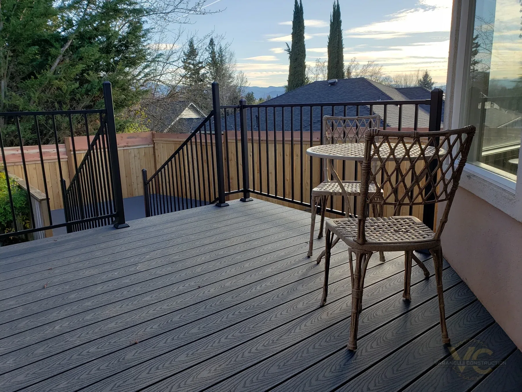 Finished split-level Trex deck with black metal railing and cedar fence in Medford, Oregon