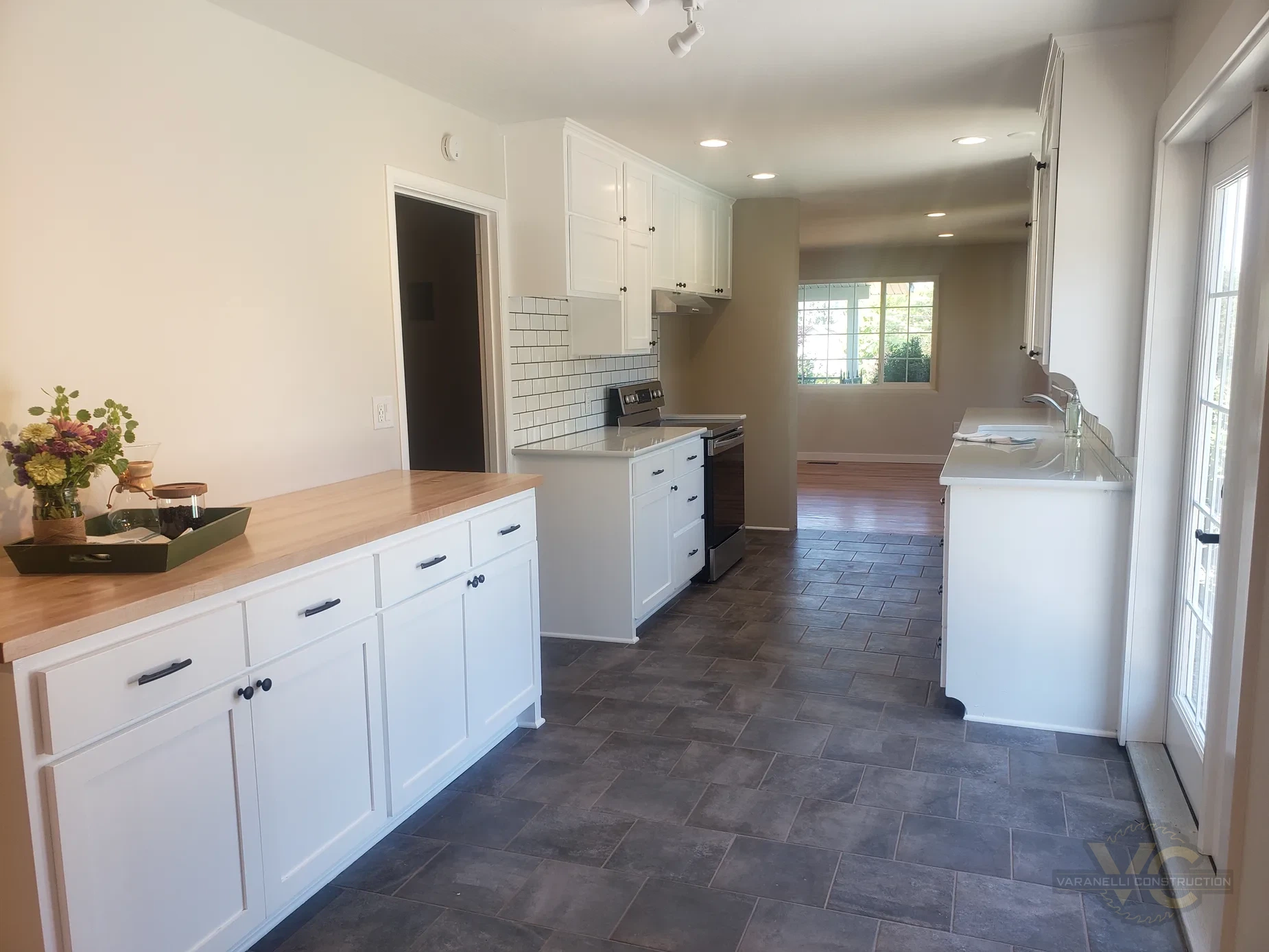 Long white kitchen remodel with gray flooring by Varanelli Construction